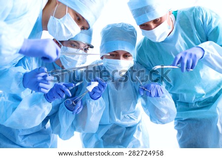 Below view of surgeons holding medical instruments in hands