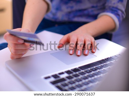 Woman sitting at the desk, shopping with laptop and credit card
