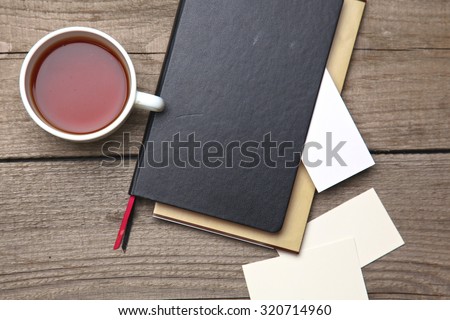 Blank business cards with pen, notebook and tea cup on wooden office table
