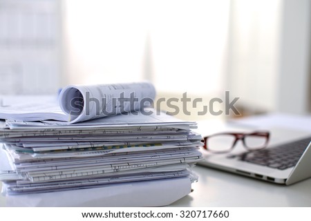 Laptop with stack of folders on table on white background