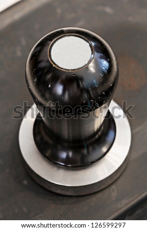 Old and stained stainless steel coffee tamper on rubber sheet