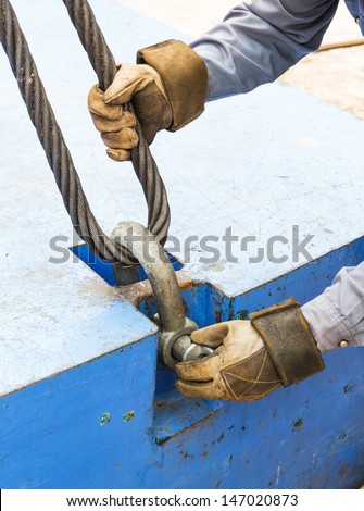 Close up worker fitting bolt anchor shackle with wire rope sling on crane counter weight