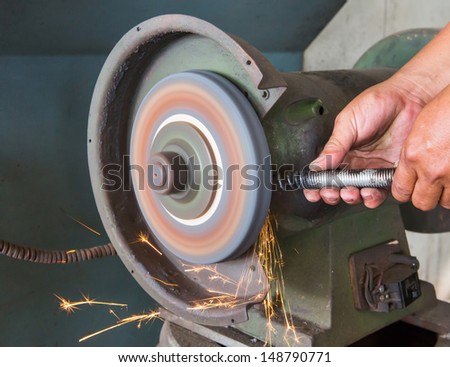 Worker using grinding wheel in car garage