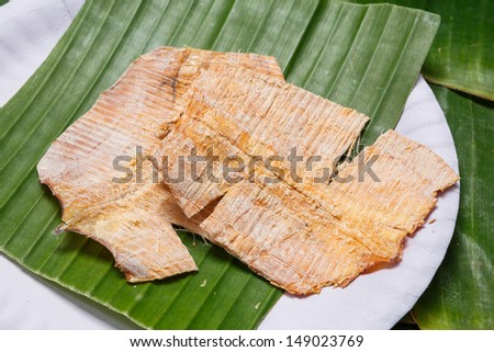 Close up Grilled dry squid on banana leaf in paper dish