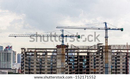 Construction crane on top of building and cloudy sky