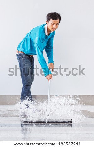 Asian worker using wiper or squeegee to clean floor surface