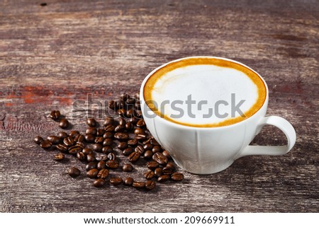 Close up one cup of coffee and roasted bean on old wooden table