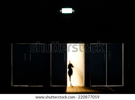 Door opened with motion blur of a man and light coming through the space