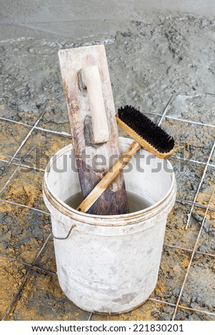 Close up old and dirty wooden trowel and brush in plastic bucket