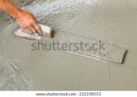 Close up worker hand using float to level surface of concrete