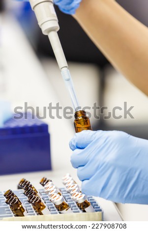 Close up scientist using auto pipette tip to transfer a specified volume of sample from vial