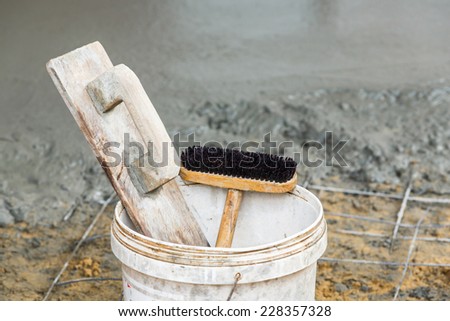 Close up old and dirty wooden trowel and brush in plastic bucket