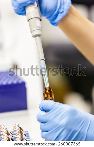 Close up scientist using auto pipette tip to transfer a specified volume of sample from vial