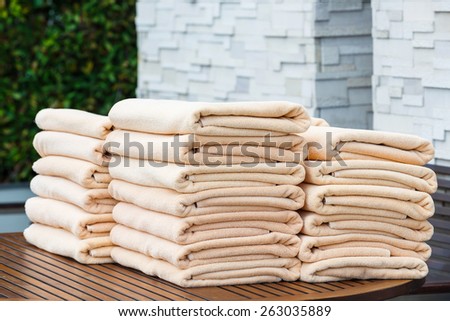 Stack of clean towel on wooden table near pool for service customer