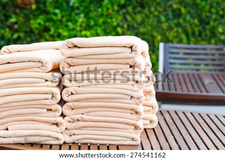 Stack of clean towel on wooden table near pool for service customer