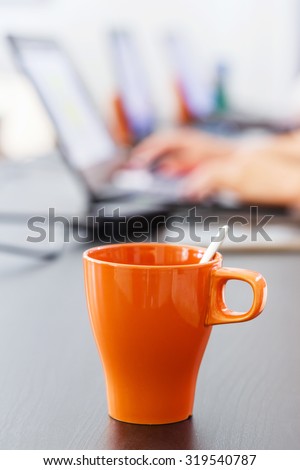 Close up coffee mug on table with blurred notebook computer background, office worker lifestyle