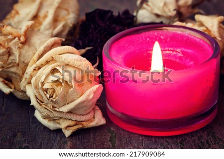 pink aroma candle and dried white roses