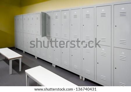 Row of steel lockers along the yellow wall and two white benches
