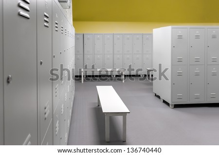 Row of steel lockers along the yellow wall and white benches