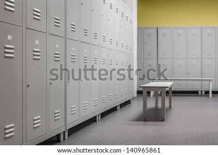 Row Of Steel Lockers Along The Yellow Wall And White Benches