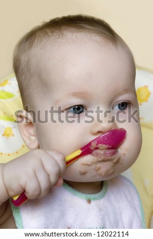baby with a spoon in a mouth