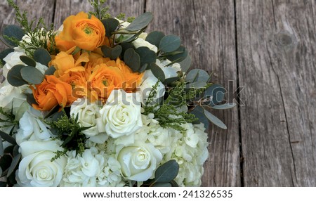 Orange and white bouquet of flowers on a farm table of distressed wood in farm country before a summer wedding, July 4, 2014