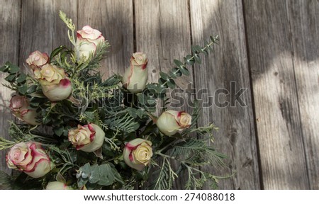 Bridal bouquet of red and white tea roses on rustic distressed wood at a French country home, the celebration of a romantic wedding in Spring.