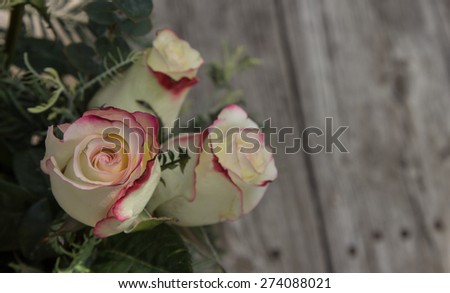 Bridal bouquet of red and white tea roses on rustic distressed wood at a French country home, the celebration of a romantic wedding in Spring.