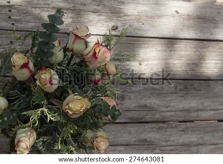 Red and white Osiria roses bridal bouquet on a rustic distressed wood table at a Valentine\'s Day wedding in the French countryside