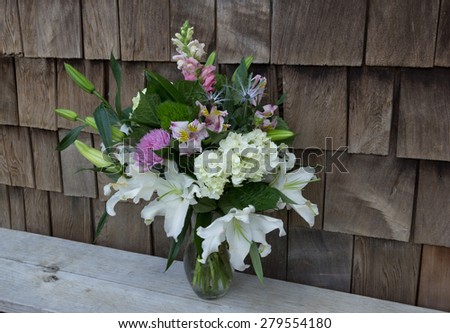Spring table bouquet at a wedding on Valentine\'s Day in the French countryside --floral arrangement contains Casablanca lilies, hydrangea, dianthus, snapdragon flowers, purple and pink mums, and more.