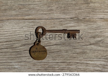 Antique old rusty sanitarium skeleton key / hospital key on a rustic wood background