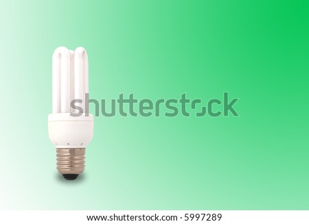 A lit up energy saving light bulb on a green background with copyspace