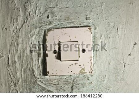 Old dirty light switch on old cracked green wall