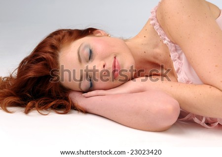 The attractive sleeping redhead women in pink slip.