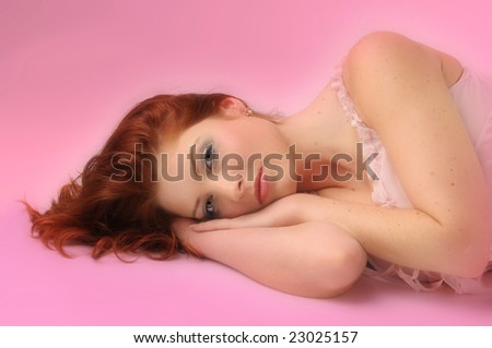 The attractive sleeping redhead women in pink slip.