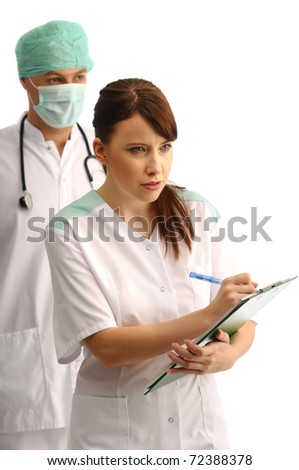 Doctor wearing cap and mask and young nurse writing notes
