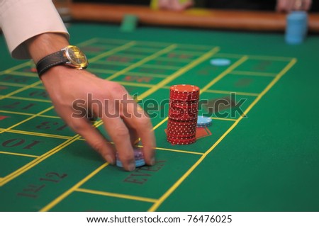 Player\'s hands betting chips on a green table