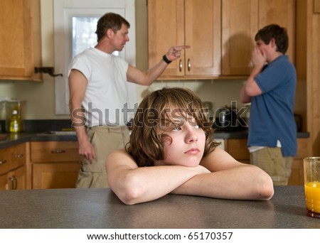 family fight - father scolds son as younger brother feels sad in foreground