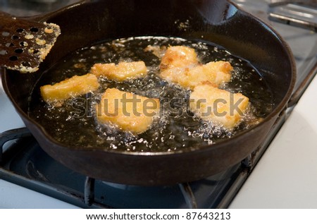 Frying corn meal mush in hot oil in an iron pan - a traditional country and soul food dish in the U.S., Latin America, and elsewhere