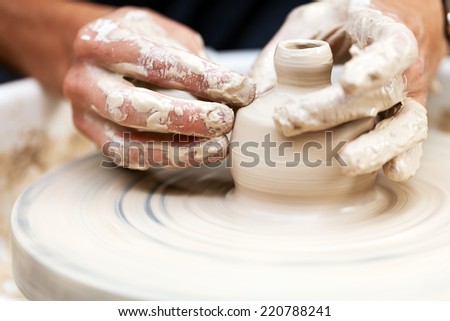 Man\'s hands creating pottery on wheel