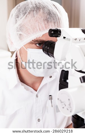 Doctor dentist using dental microscope in modern dental office for operation of a woman patient -Dentistry