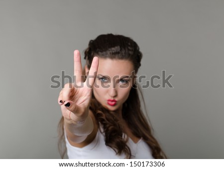 Beautiful sexy woman with red lips in white shirt showing two fingers and wished for peace