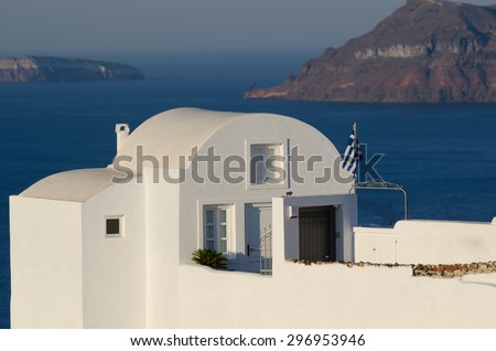 White House with the flag of Greece, stands on top of a cliff in the town of Oia on the Greek island of Santorini
