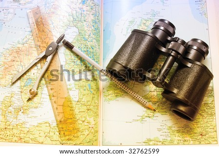 Binoculars, compasses and ruler over world map