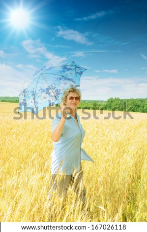 Senior woman with parasol under bright sun