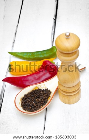 Peppers and pepper shaker on wooden backdrop