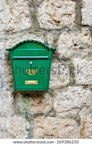 Green mailbox on stone wall