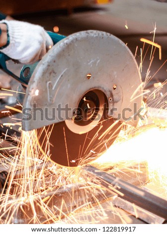 Closeup of a metal cutting saw slicing through a steel pipe.
