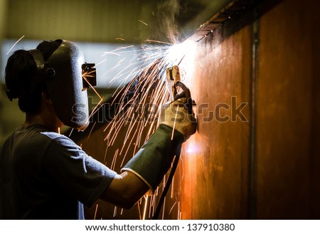 Worker With Protective Mask Welding Metal And Sparks