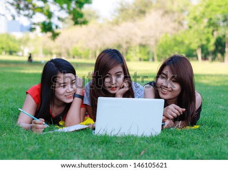 Young students group with computer studying in spring outdoors